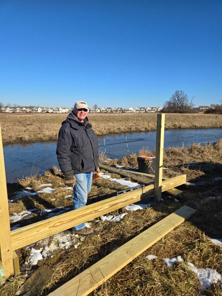 Volunteer stands next to the framing of the new wetland deck.